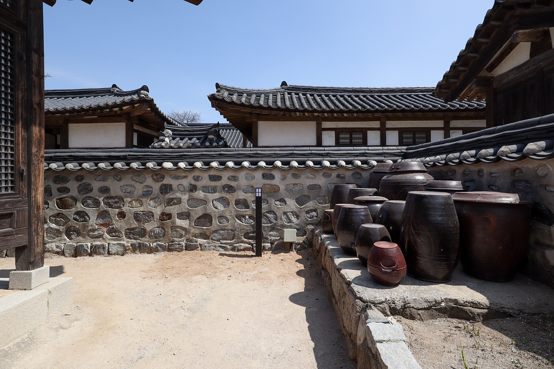 Storage jars and a hanok beyond the wall.