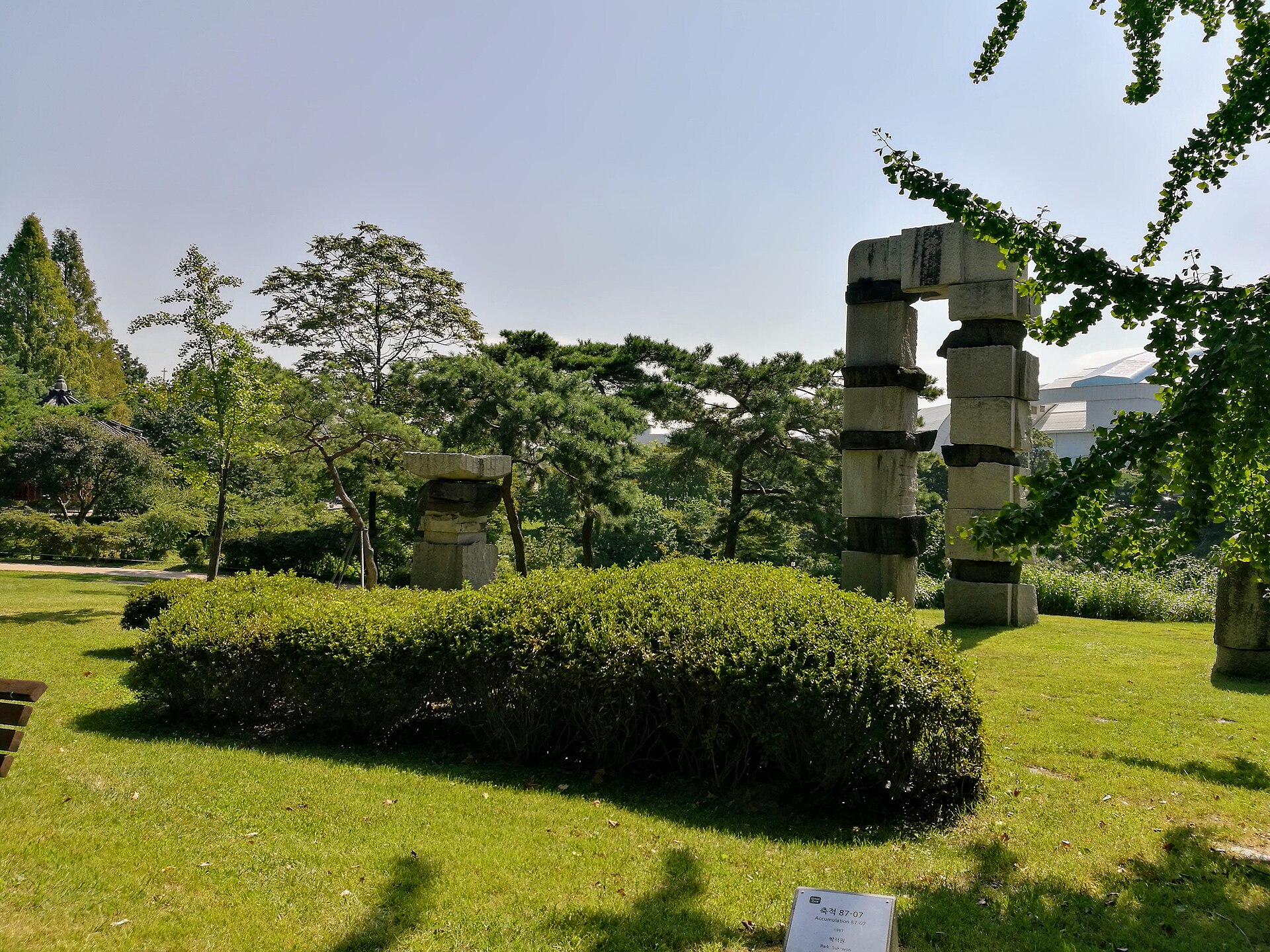 An outdoor sculpture set among lawn and trees.