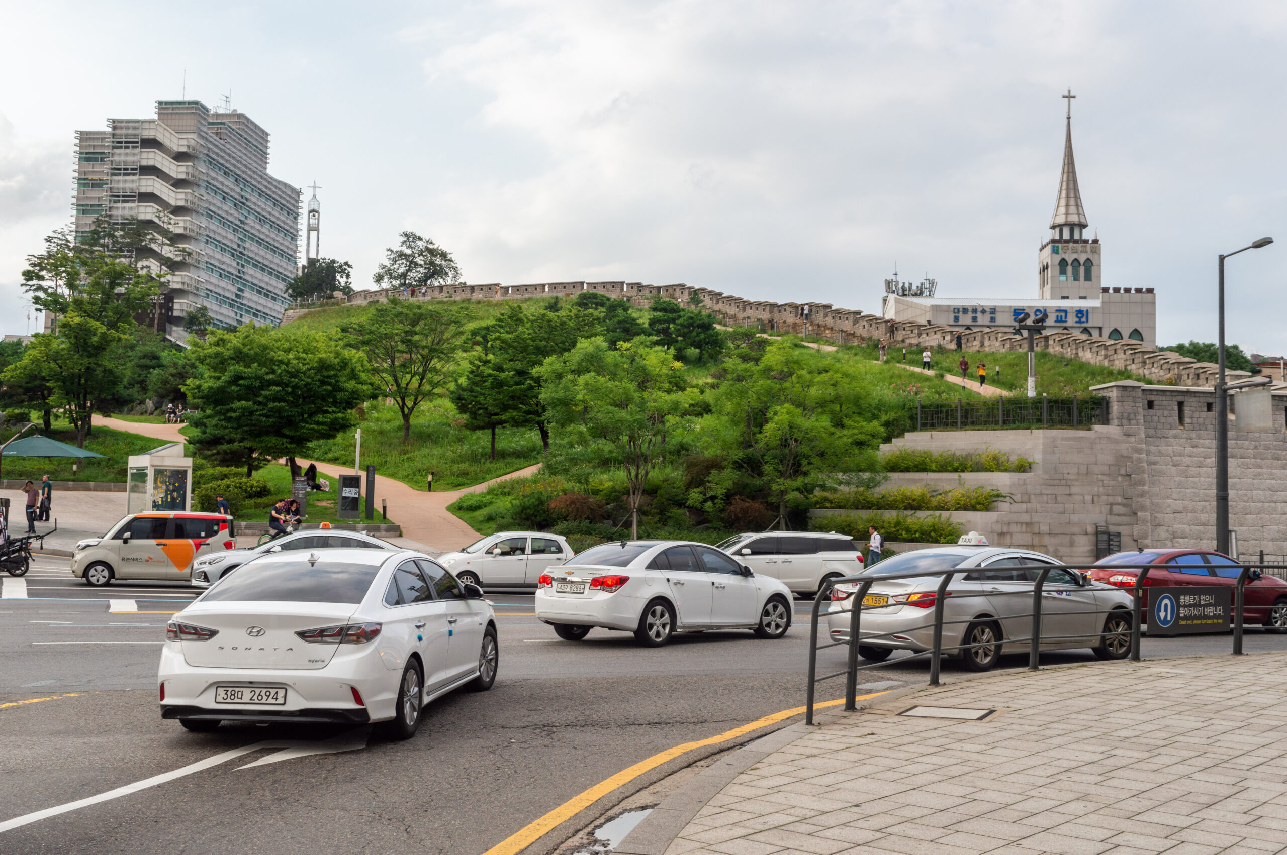 Heunginjimun Park's green slope and city wall above the road in August 2019