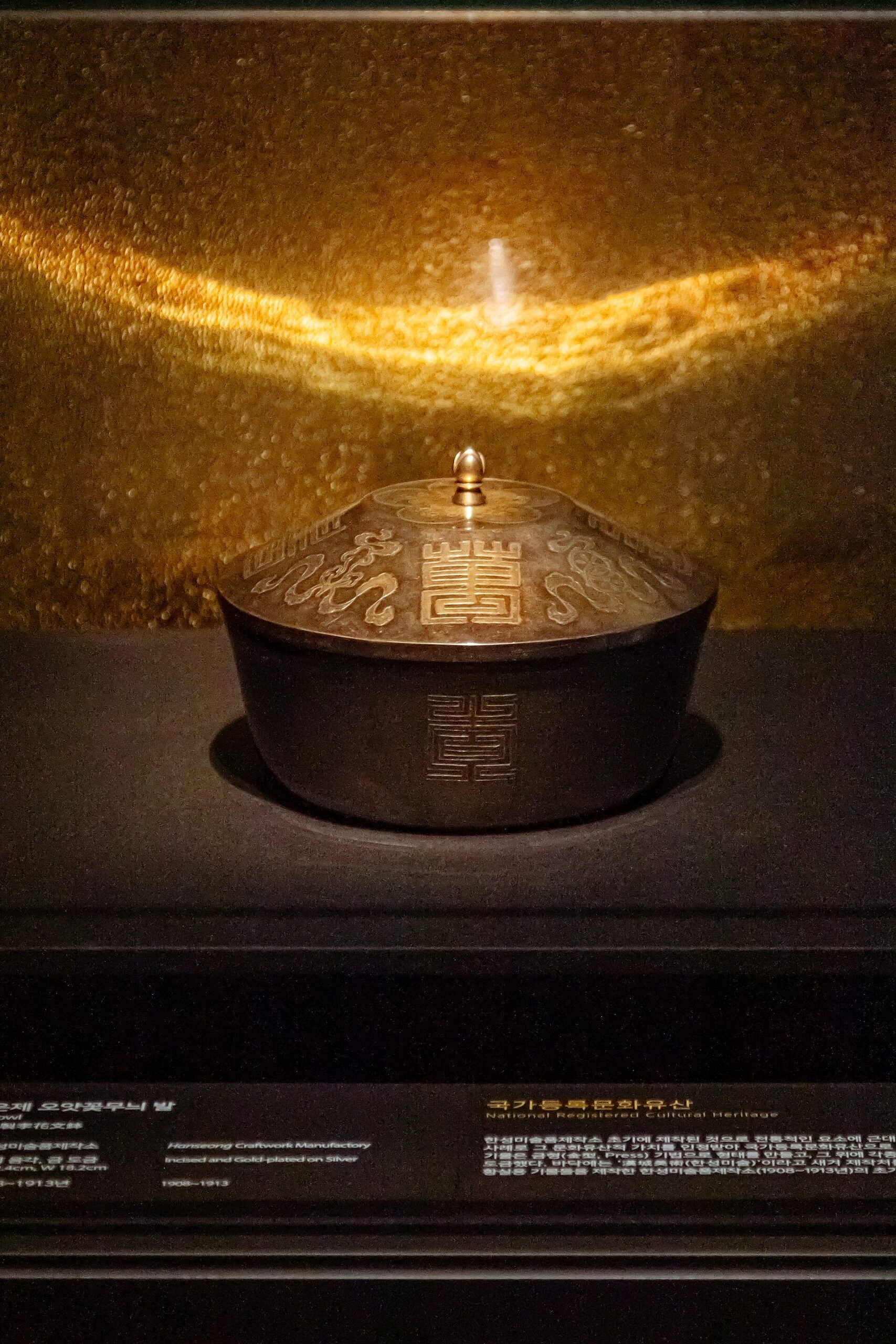 Lidded metal vessel photographed in the museum's historical display