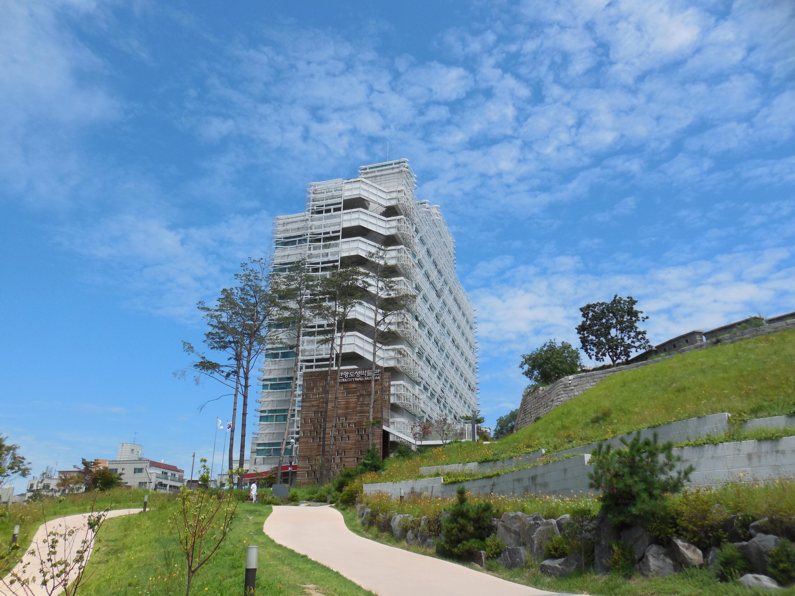 White exterior of Seoul City Wall Museum beside the grassy slope, photographed in July 2015