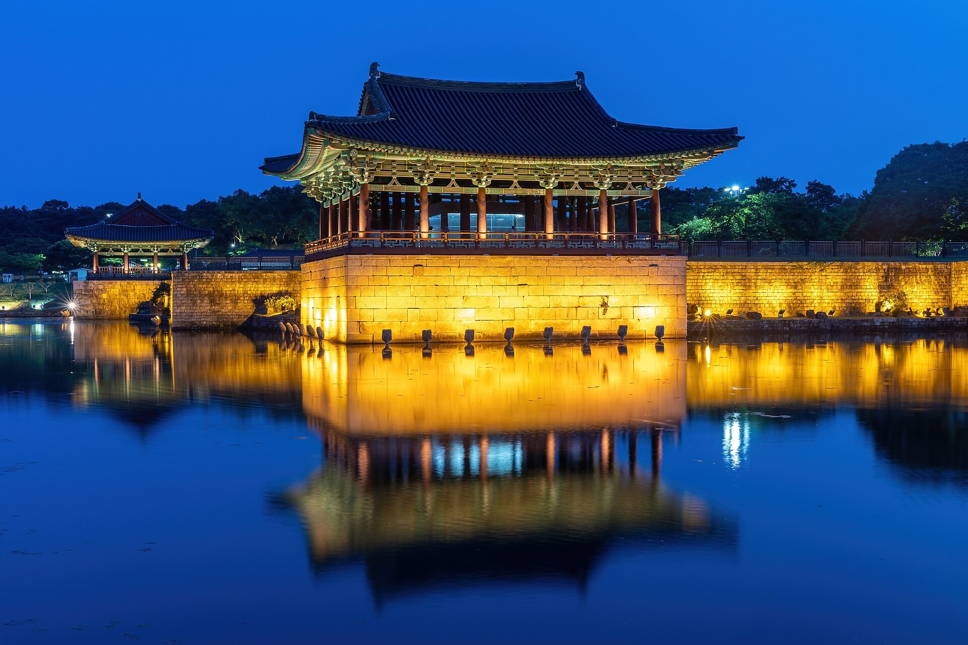 Illuminated palace pavilion reflected in Wolji Pond at blue hour